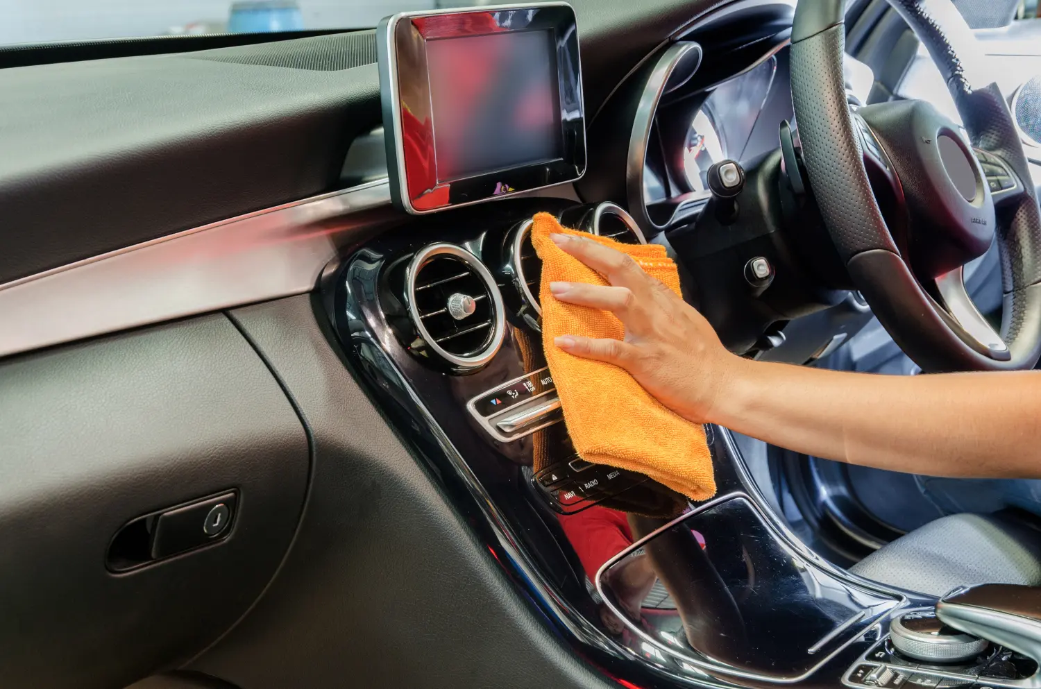 Hand mit Mikrofasertuch reinigt den Innenraum des Autos