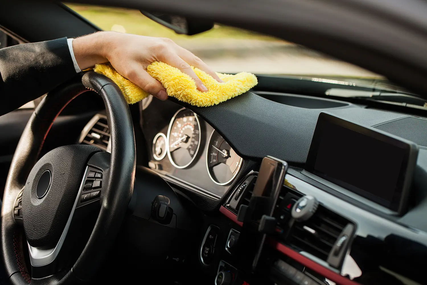 Hand mit Mikrofasertuch reinigt den Innenraum des Autos